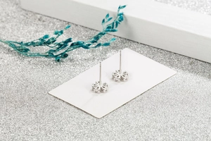 Detailed view of silver five-petal flower stud earrings with sparkling crystals