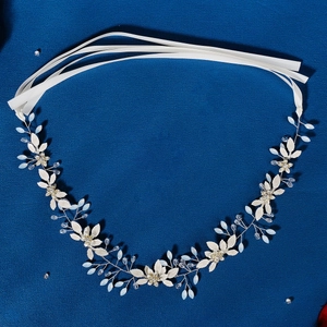 Dettaglio della fascia da sposa argento con fiori in tessuto bianco e perline opale