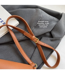 Close-up of adjustable brown leather shoulder strap with gold metal buckle on a handbag