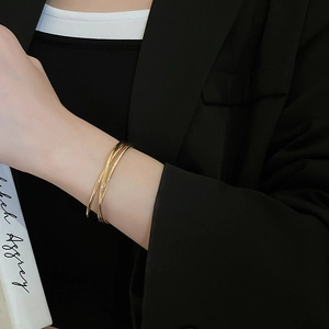 Close-up of a triple-layered gold wave bangle bracelet worn on a model's wrist