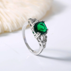 Detailed close-up of emerald green square cut gemstone ring with micro-pave zircon accents