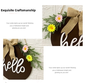 Detail of hello wooden door wreath with burlap bow and artificial daisies on dark wood