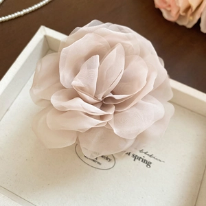Detailansicht eines eleganten mehrlagigen Stoffblumen-Haargummis aus zartrosa Chiffon