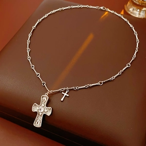 Macro shot of silver cross necklace with pavé cubic zirconia on textured leather box
