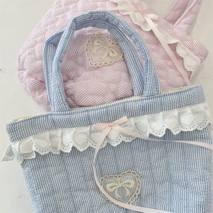 Detail of quilted cotton bucket bag with lace heart embroidery and pink silk ribbon