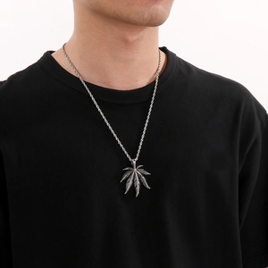 Gros plan d'un pendentif feuille d'érable punk en acier inoxydable avec turquoise sur un mannequin