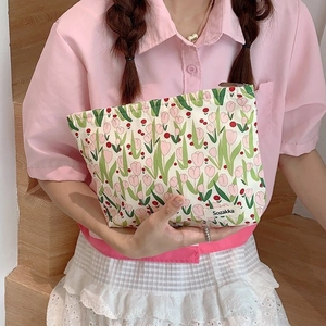 Handheld canvas tulip cosmetic bag with floral print and zipper closure in a lifestyle setting