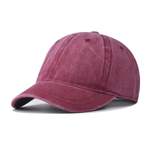Detail view of burgundy washed cotton fabric and stitching on a short brim baseball cap