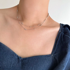 Close-up of double-layered silver beaded titanium steel necklace on model neck