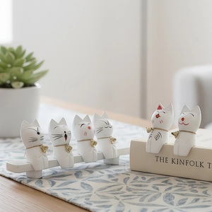 Set of six white resin kitten figurines with gold bells on a wooden desktop