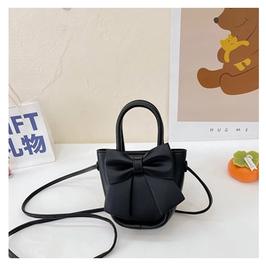 Detail view of mini black crossbody bag with large decorative bow on matte leather