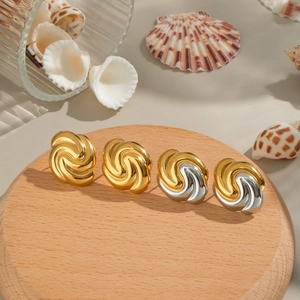 Textured swirl stud earrings in 18K gold and silver finish on a wooden tray with shells