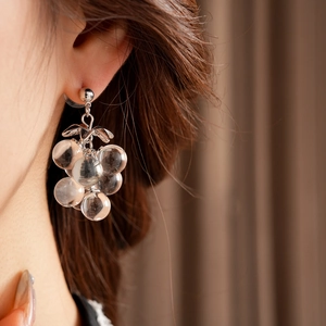 Detail of crystal grape tassel stud earrings with silver leaves on model's ear