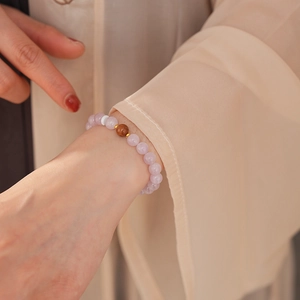 Close-up of pink beaded bracelet with brown accent on model wearing silk garment