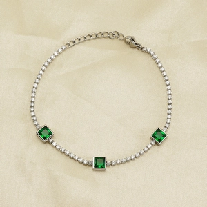 Detail of silver tennis bracelet with emerald-cut green zircons on champagne silk