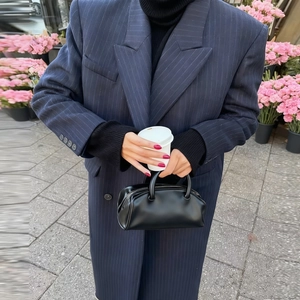 Women's chic navy blue striped long coat paired with a black leather handbag