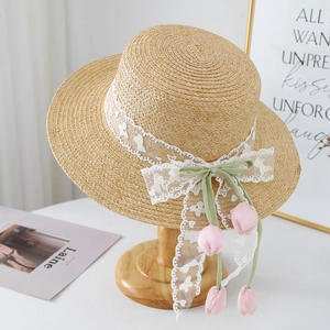 Detail of raffia flat top hat with white lace and green ribbon featuring tulip charms