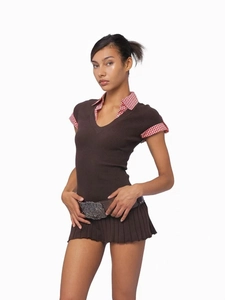 Detalle de polo de punto marrón estilo Y2K con cuello a cuadros y falda de tablas