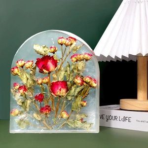 Macro detail of arch-shaped resin ornament with preserved red roses and green leaves