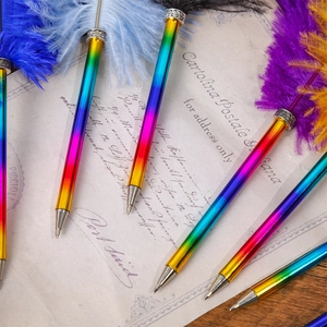 Rainbow gradient feather ballpoint pens set against a vintage postcard background