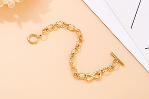 Detail shot of golden infinity charm bracelet with T-Bar toggle clasp on elegant background