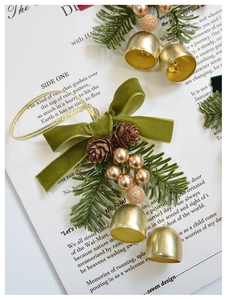 Detailed view of Christmas bell with green velvet bow and pine cones on paper