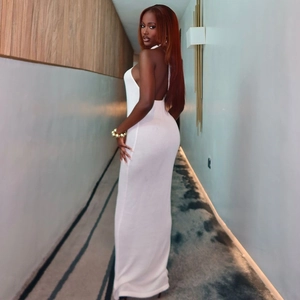Close-up of the backless halter design and metal accents on a white knitted maxi dress