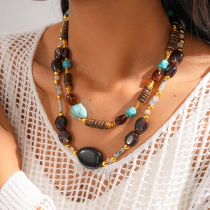 Detail of layered bohemian necklace with turquoise beads and black oval pendant on model