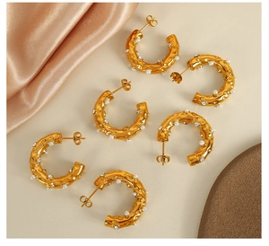 Close-up of gold-plated C-shaped hoop earrings with hammered texture and inset pearls