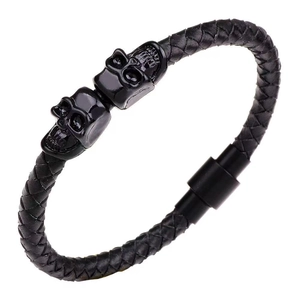 Detail of black braided leather bracelet featuring metal skulls and magnetic clasp