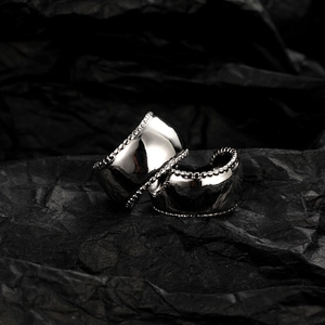 Minimalist wide silver metal ear cuffs with beaded edge on black textured background