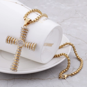 Detailed view of a gold cross pendant with rhinestones on a square box chain