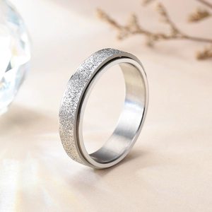 Macro shot of silver spinner ring with a matte frosted texture on a neutral background