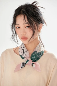 Detail of model wearing a paisley cotton linen scarf in pink and green with gold earrings
