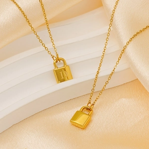 Detailed close-up of golden titanium steel padlock necklaces with letter D on silk fabric
