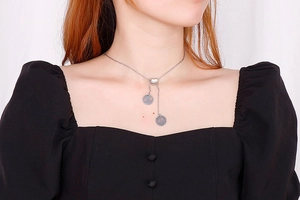 Close-up of heart-shaped titanium steel Y-necklace with round charms on female model