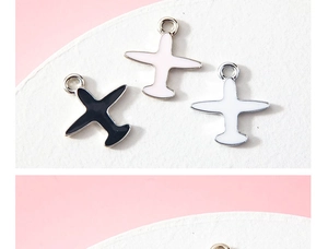Detailed view of three colorful enamel airplane charms in black, white and pink colors