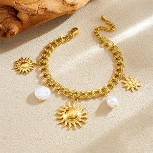 Gold plated vintage sun star and pearl charms chain bracelet on a neutral stone base