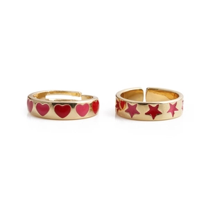 Detail view of gold adjustable rings featuring red and pink enamel heart and star patterns