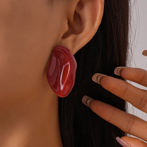 Close-up of a model wearing a red irregular geometric drip oil stud earring with glossy finish