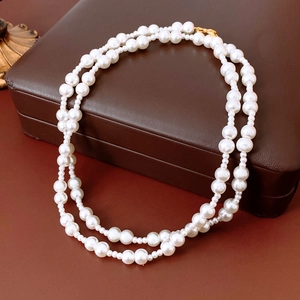 Detail of double-layer white pearl necklace with gold clasp on a leather jewelry box