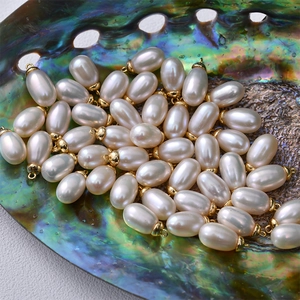 Close-up of natural oval white pearls with gold caps in a colorful abalone shell