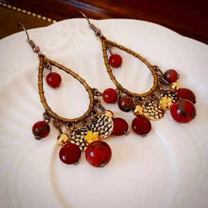 Détail de boucles d'oreilles en bronze rétro avec perles rouges et glands métalliques