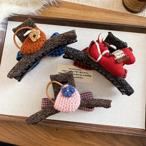 Close-up of three Korean fabric bow hair claws with crochet flowers and red pony charm