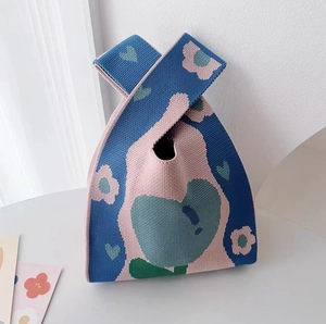 Close-up of the blue and pink knitted tote bag with floral and heart patterns