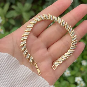 Mano che tiene un bracciale a cuore geometrico placcato in oro con zirconi a pavé