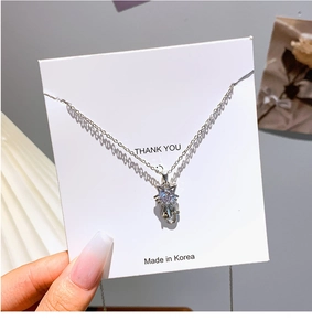 Macro shot of silver kitten pendant necklace with sparkling cubic zirconia on jewelry card