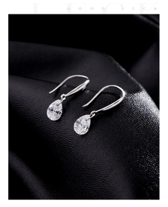 Vue macro des boucles d'oreilles goutte en argent avec zircon sur texture cuir noir