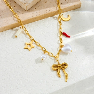 Golden stainless steel necklace featuring star moon heart and bow charms on stone surface