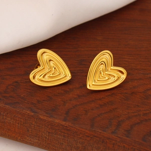 Exotic vintage heart-shaped gold stainless steel earrings on a wooden background